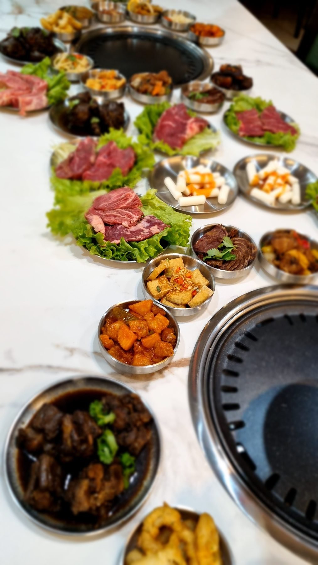 Mesa servida con banchan, carnes marinadas y parrilla
